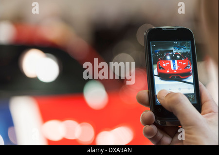 Ein Besucher der Zürich Motor Show in Zürich nimmt ein Bild von einem Ferrari F458 Speciale-Luxus-Sportwagen mit seinem iPhone Stockfoto