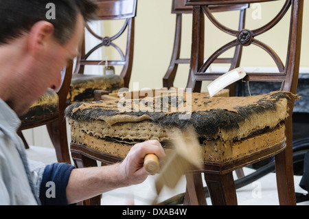Ein professionellen Restaurator entfernt die Abdeckung und die Polsterung aus einem antiken Stuhl Stockfoto