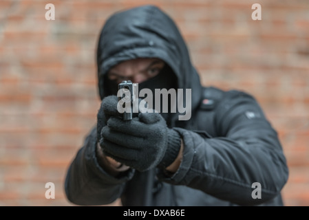 Mann mit Maske mit Pistole Stockfoto