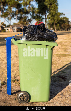 Wheelie bin im Park überfüllt. Stockfoto