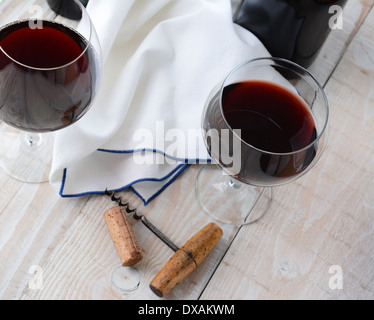 Schrauben Sie zwei Weingläser Rotwein auf einem Holztisch mit antikem Kork. Querformat aus einem hohen Winkel geschossen. Stockfoto