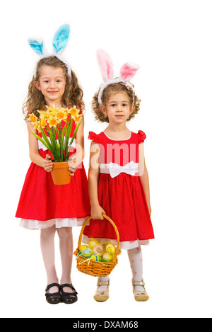 Zwei Schwestern Schönheit mit Hasenohren holding Ostereier im Korb und Blumen isoliert auf weißem Hintergrund Stockfoto