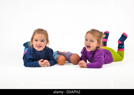 Zwillinge auf dem Bauch liegend, spielen und lachen Stockfoto