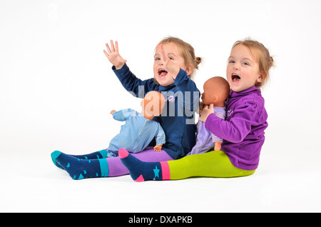 Zwillingen mit Puppen spielen und lachen Stockfoto