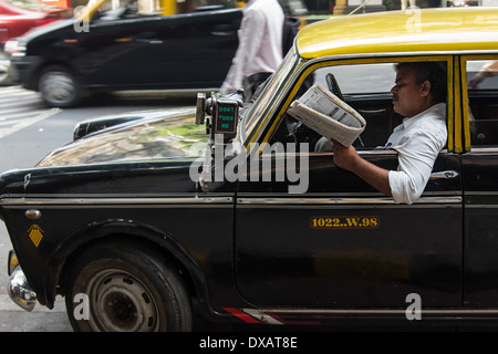 Indischer Taxifahrer in alten Taxi mit Taxameter auf außerhalb Auto in Mumbai, Indien Stockfoto