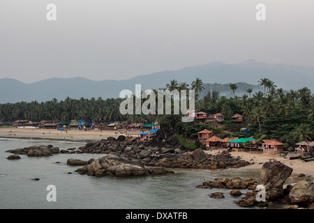 Strandhütten mit Kokospalmen und Berge im Hintergrund in Palolem Beach in Goa, Indien Stockfoto