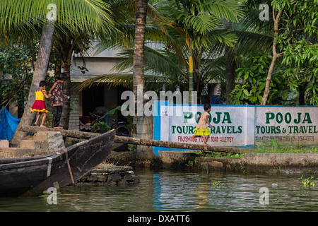 Kinder gehen und laufen über einen Baumstumpf, überqueren den Fluss in den Backwaters von Alleppey in Kerala, Indien Stockfoto