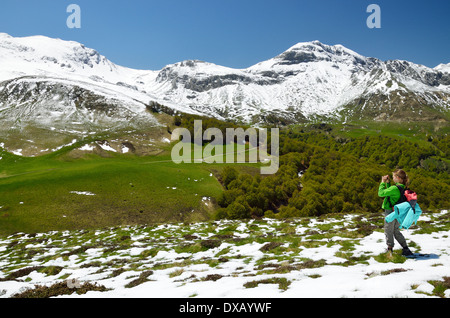 Mädchen auf dem grünen Hügel mit Schnee im Frühjahr Pyrenäen Stockfoto