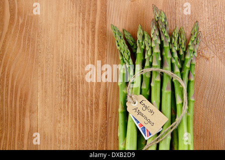 Eine lose Reihe von frischem grünen Spargel Stiele mit Etikett gegen rustikal, Vintage Holz Hintergrund, UK - mit Textfreiraum. Stockfoto
