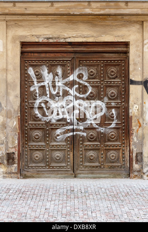 Historische Schwere Holztüren entstellt mit Graffiti an einem verlassenen Gebäude in Prag, Tschechien. Stockfoto
