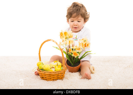 Kleinkind Jungen mit Osterkorb arrangieren Narzissen in einem Topf und sitzen auf Teppich Stockfoto