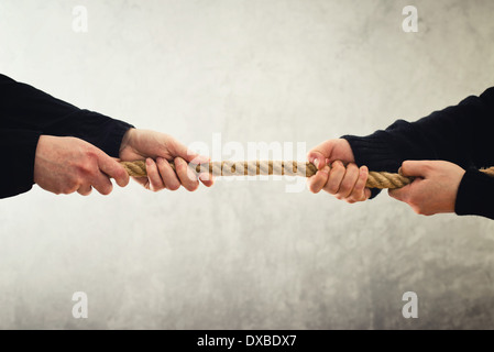 Tug Of War. Weibliche Hände Zugseil auf gegenüberliegenden Seiten. Rivalität Konzept. Stockfoto