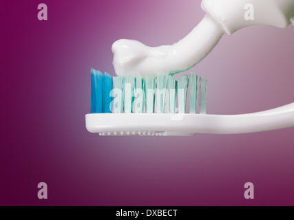 Zahnbürste mit Paste auf violettem Hintergrund Stockfoto