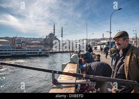 Fischer am Galata Brücke mit der Yeni oder New Moschee Eminönü und im Hintergrund die Skyline von Istanbul. Istanbul, Türkei. Stockfoto