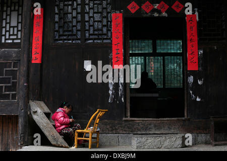 Enshi, Chinas Provinz Hubei. 23. März 2014. Peng Pan, ein sechs-jährigen Mädchen spielt bei ihr zu Hause in Pengjiazhai Dorf in Enshi, Zentral-China Hubei Provinz, 23. März 2014. Gestelzt Gebäude der Tujia ethnischen Gruppe, vor allem in Zentral-China Hunan und Hubei Provinz gesehen ist ein Juwel der chinesischen Residenz. Pengjiazhai Dorf gehört zu den reservierten Bereichen für Tujia gestelzt Gebäude. © Ren Zhenglai/Xinhua/Alamy Live-Nachrichten Stockfoto