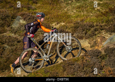 Biker sein Fahrrad auf einem steilen Hügel in der Landschaft Stockfoto