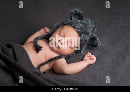 Schlafenden neugeborenen Jungen tragen ein graues gehäkelt-Wolf-Hut. Stockfoto