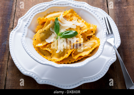 Butternut-Kürbis Mezzaluna Ravioli oder Tortellini in einer Schüssel auf rustikalen Holz Stockfoto