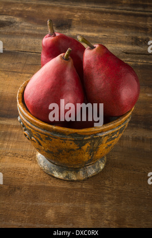 Anjou rote Birnen in rustikalen Schüssel auf rustikalen Holz Stockfoto