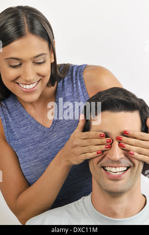 Weibliche junge Erwachsene Holding übergibt den Augen des Mannes Stockfoto