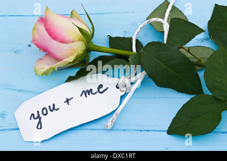 Eine rosa Rose auf einem blauen Hintergrund und eine personalisierte Tag sagen: "you and me". Perfekt für Verliebte und für den Valentinstag. Stockfoto