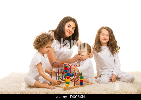 Lächelnde Mutter mit drei Kindern zu Hause zu spielen, mit Holzspielzeug Stockfoto