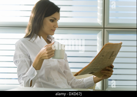 Berufstätige Frau, Zeitung lesen und Kaffee trinken Stockfoto
