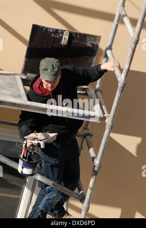 Arbeiter klettern Gerüst halten Malwerkzeuge. Stockfoto