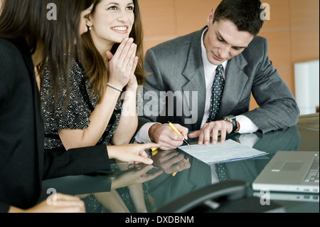 Junger Mann unterschreiben, berufstätige Frau zeigen Stockfoto