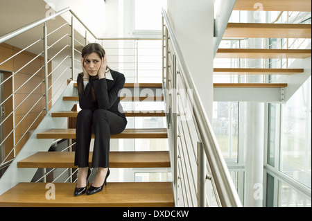 Geschäftsfrau auf Büro Treppe hielt ihren Kopf Stockfoto