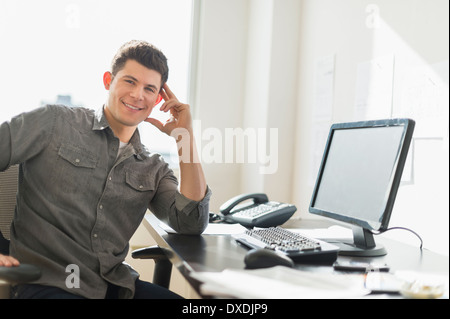 Junger Mann sitzt vor der Rezeption Stockfoto