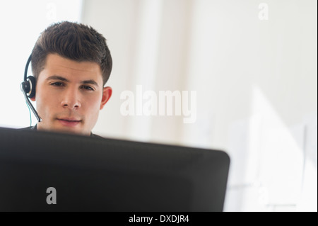 Junger Mann vor Schreibtisch sitzen und reden Stockfoto