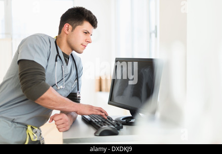 Junger Mann mit Stethoskop am Computer arbeiten Stockfoto