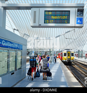 Backpackers Gruppe Bahnhof Plattform mit Rucksack Kit in modernen öffentlichen Verkehrsmitteln Glasdach Gebäude Anzeigetafel Belgien Lüttich geladen Stockfoto