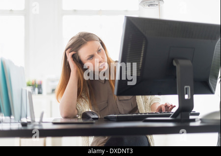 Porträt der jungen Frau, die Arbeiten am Computer im Büro Stockfoto