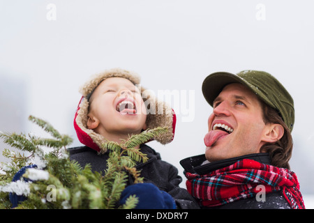 Vater und Sohn (6-7) fangen Schneeflocken auf der Zunge Stockfoto