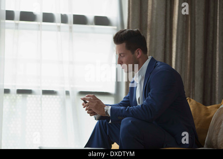 Junger Geschäftsmann sitzt innen und Text-messaging, New York City, New York State, USA Stockfoto