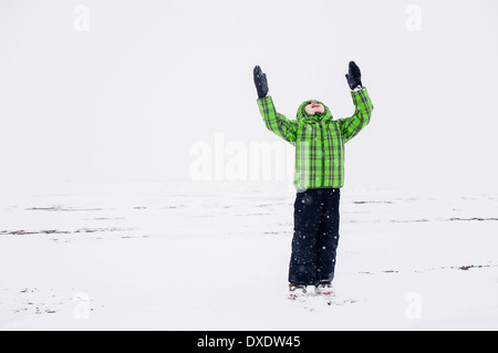 Junge (4-5) mit erhobenen Armen in verschneiter Landschaft, Colorado, USA Stockfoto