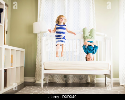 Mädchen (4-5) und jungen (8-9) springen auf sofa Stockfoto