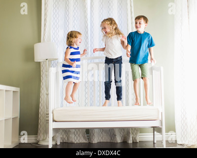 Mädchen (4-5, 6 und 7) und jungen (8-9) springen auf sofa Stockfoto