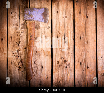 Eine alte Axt mit Holzgriff und tragen Marken sitzt auf einem rauen Holz-Hintergrund Stockfoto