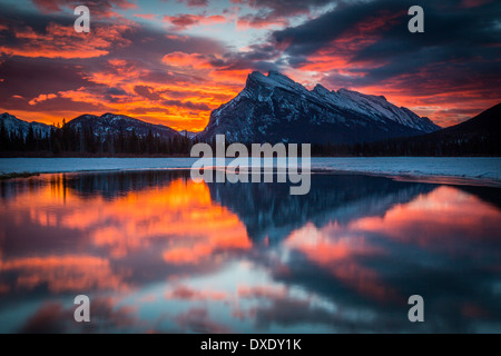 Sonnenaufgang im Banff National Park.  Dawn leuchtet in den Wolken über Mount Rundle und spiegelt sich in Vermilion See. Stockfoto