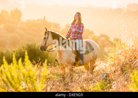 American Quarter Horse. Reiter auf Dun Wallach stehen. Toscana, Italien Stockfoto