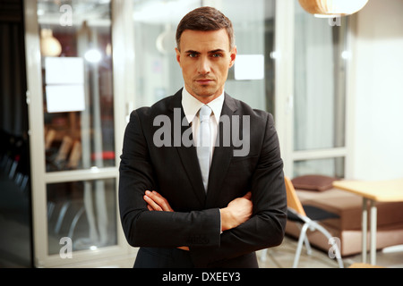 Zuversichtlich Geschäftsmann mit im Büro verschränkten Armen stehend Stockfoto