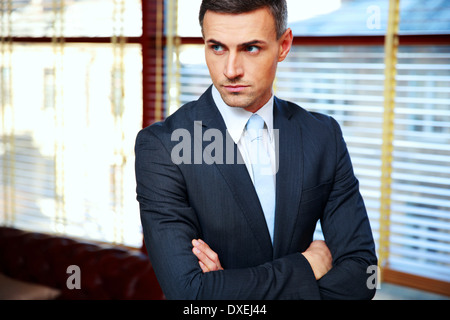 Gut aussehend Geschäftsmann mit im Büro verschränkten Armen Stockfoto