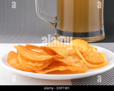 Tasse frisch gezapftes Bier und Platte mit Haufen Pommes frites Stockfoto