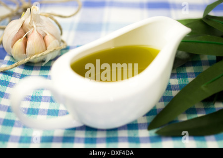 Olivenöl in eine Sauciere mit Knoblauch und Olivenblätter Stockfoto