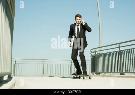Geschäftsmann mit Handy während Skateboarding, Mannheim, Baden-Württemberg, Deutschland Stockfoto