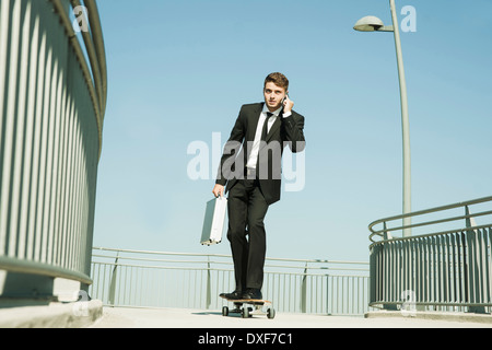 Geschäftsmann mit Handy während Skateboarding, Mannheim, Baden-Württemberg, Deutschland Stockfoto