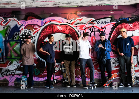 Junge Skateboarder, gegen einen grafitti bedeckte Wand an der South Bank Skateboard Park in London. Stockfoto